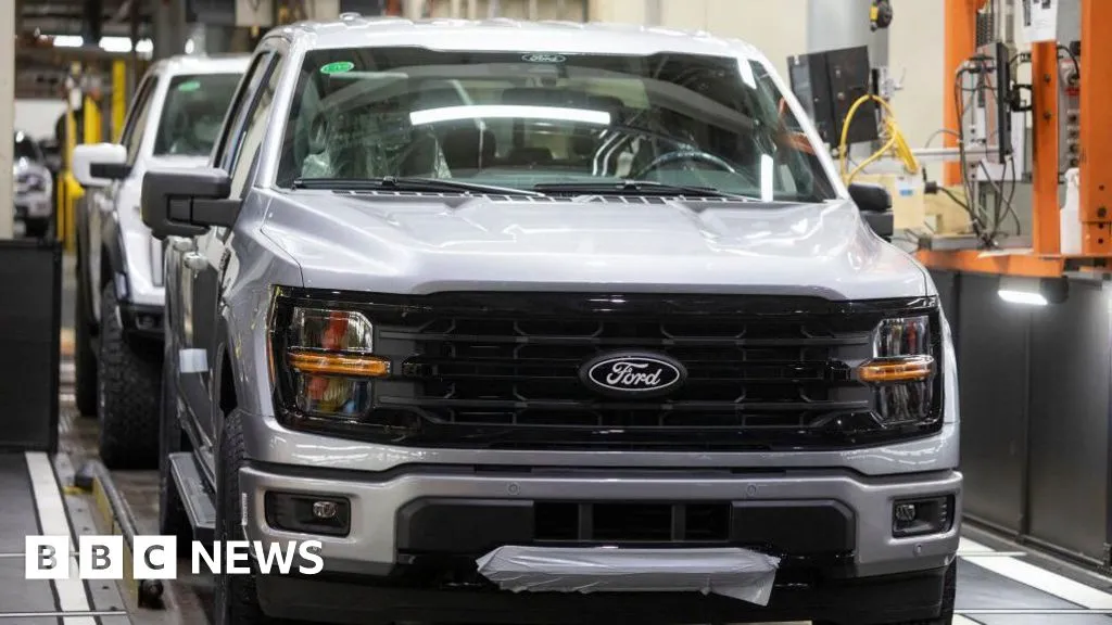 Engenheiro humano inspecionando veículo em fábrica da Ford, com câmeras e sensores visíveis